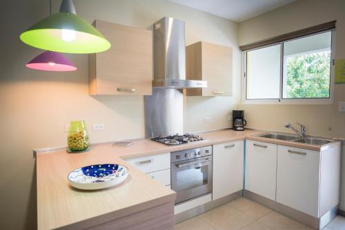 a kitchen with white cabinets and a stove top oven at Costa Esmeralda Village in Palm-Eagle Beach