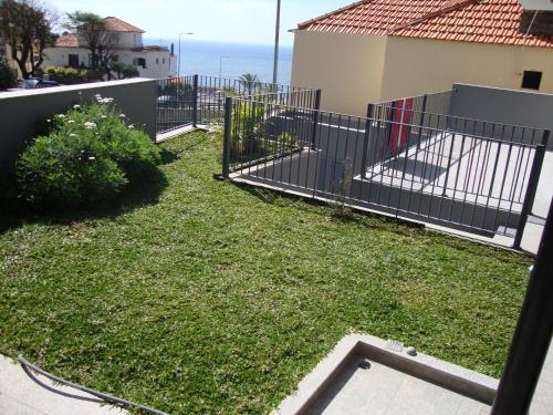 a yard with a fence and grass at Casa da Praia in Calheta