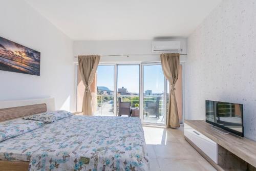 a bedroom with a bed and a flat screen tv at Apartments DILARA in Čanj