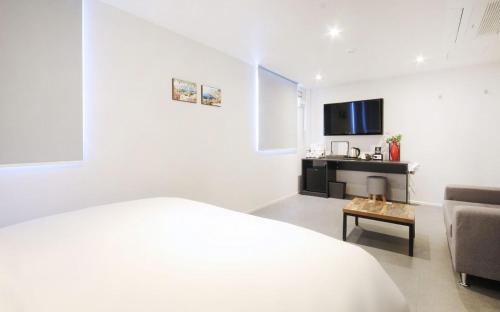een witte kamer met een bed, een bank en een tafel bij Hotel Maison in Busan