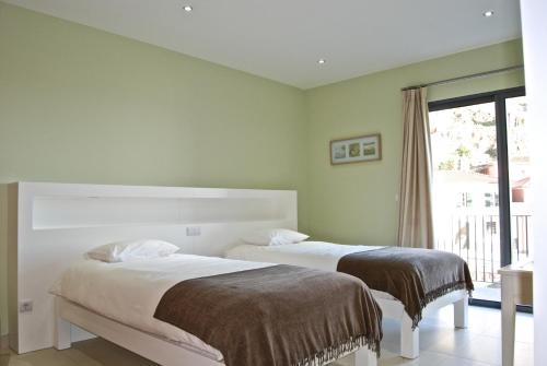 two beds in a bedroom with a window at Casa da Praia in Calheta