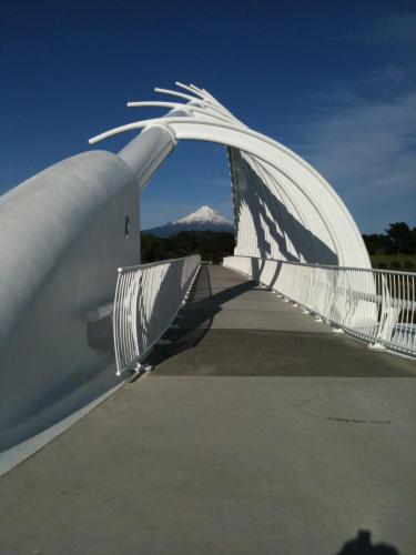 a white bridge with a mountain in the background at Luxury Home Next to Ocean and Walkway in New Plymouth