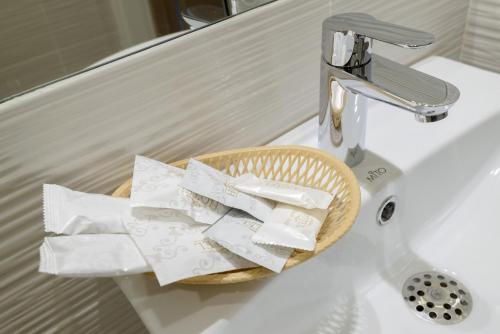 a basket of toilet paper sitting on a bathroom sink at Aterrasuite Hotel in Novosibirsk