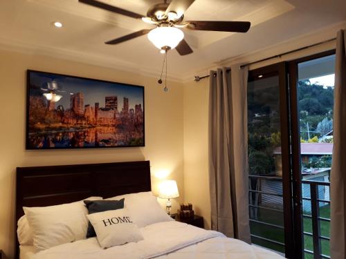 a bedroom with a bed with a ceiling fan and a window at Mirango Apartments in Boquete