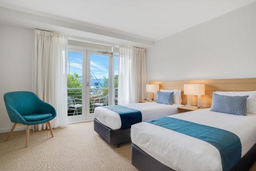 una habitación de hotel con 2 camas y una silla en Aligned Corporate Residences Williamstown en Williamstown
