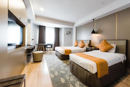Habitación de hotel con 2 camas y escritorio en L'Fisher Hotel Bacolod, en Bacolod