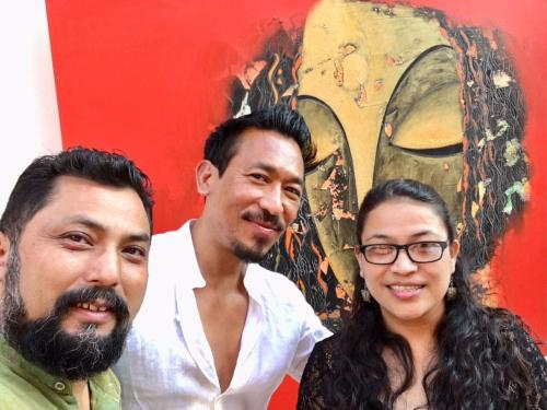 two men and a woman standing in front of a painting at Dalai-La Boutique Hotel in Kathmandu