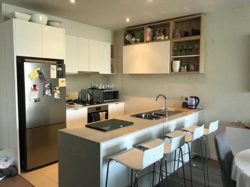 a kitchen with white cabinets and a counter with bar stools at Marina View Apartment on the Maribyrnong River, Melbourne in Maribyrnong