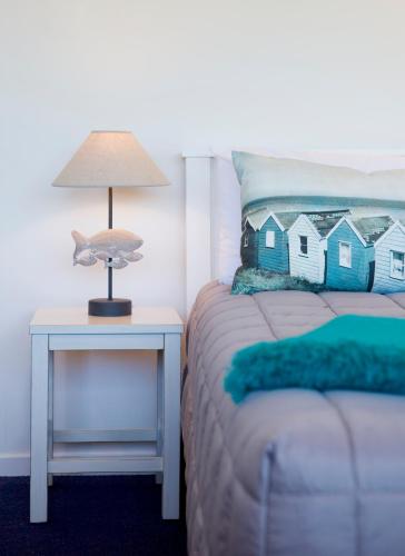 a bed with a lamp on a night stand next to a side table at Motel Oasis in Gisborne