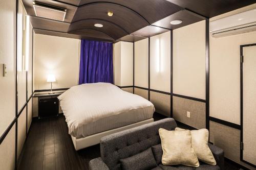 a small bedroom with a bed and a couch at Hotel Aqua Color (Adult only) in Fukushima