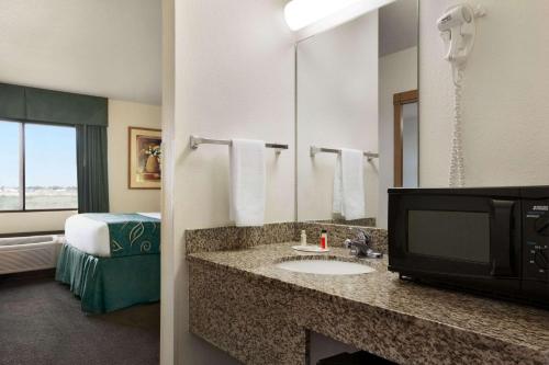 a hotel room with a bathroom with a sink and a television at Travelodge by Wyndham Pecos in Pecos