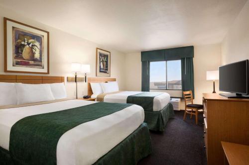 a hotel room with two beds and a flat screen tv at Travelodge by Wyndham Pecos in Pecos