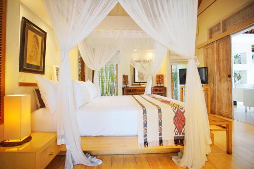 a bedroom with a canopy bed with white curtains at Villa Bali Asri Batubelig in Seminyak
