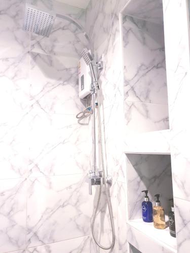 a shower in a bathroom with a white marble wall at Hotel Chuan Chom The High Resort Saraburi - SHA Plus in Sara Buri