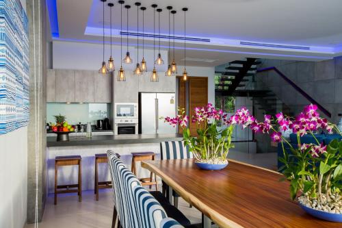 a kitchen and dining room with a wooden table with flowers at Villa Momo Private Pool near Kata Beach in Kata Beach