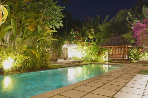 a swimming pool in a garden with a gazebo at Villa Bali Asri Batubelig in Seminyak