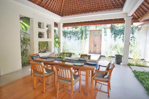 a dining room with a wooden table and chairs at Villa Bali Asri Batubelig in Seminyak