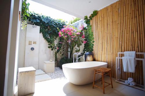 a bathroom with a tub and a shower with flowers at Villa Bali Asri Batubelig in Seminyak
