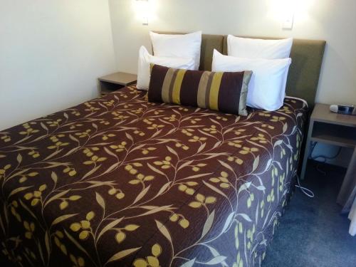 a hotel room with a bed with a brown blanket and pillows at Marineland Beachfront Accommodation in Napier