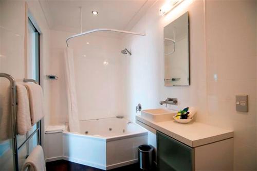 a bathroom with a sink and a tub and a mirror at Marineland Beachfront Accommodation in Napier