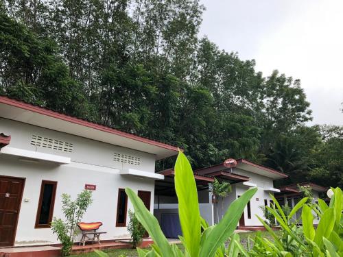 uma casa branca com um telhado vermelho em Thanathorn Guesthouse em Trang