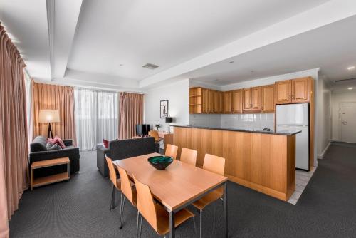 a kitchen and a living room with a table and chairs at Franklin Apartments in Adelaide