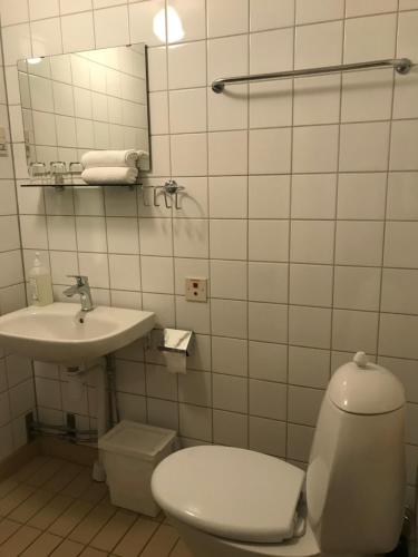 a white bathroom with a toilet and a sink at Klackbergsgården in Norberg