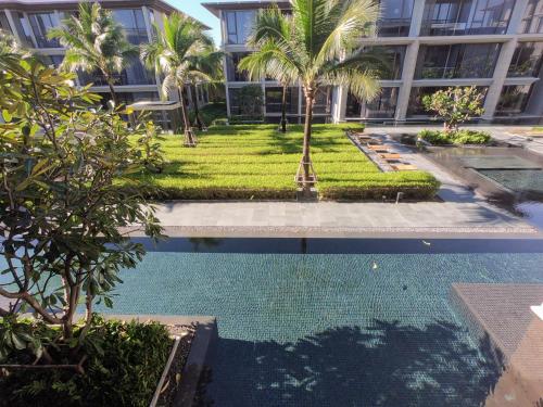 a swimming pool in front of a building with palm trees at Baan Mai Khao condo in Mai Khao Beach