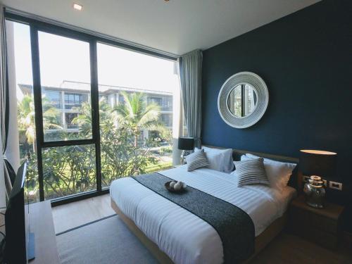 a bedroom with a large bed and a mirror at Baan Mai Khao condo in Mai Khao Beach