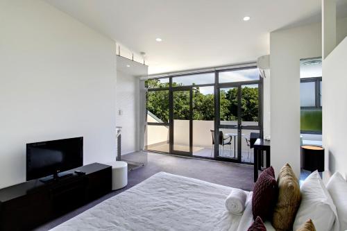a bedroom with a large bed and a television at Byron Butter Factory Apartments in Byron Bay