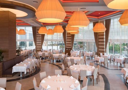 a restaurant with white tables and chairs and chandeliers at Ramada Plaza by Wyndham Rize in Rize