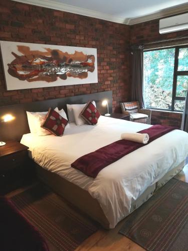 a bedroom with a large bed with a brick wall at 24 Onvrey Guest House in Boksburg