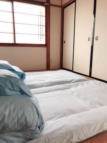 a bedroom with two white beds and a window at Guest House Asahi in Otaru