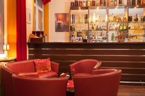 a bar with two red chairs and a counter at Kulturhotel Kaiserhof in Bad Liebenstein