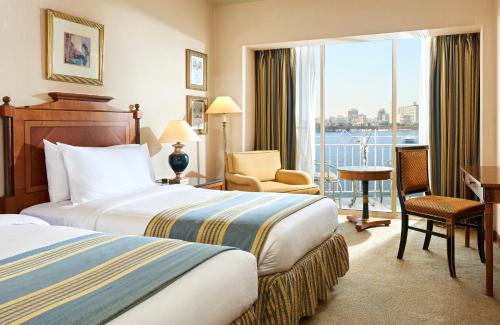 a hotel room with two beds and a balcony at Hilton Cairo Grand Nile in Cairo