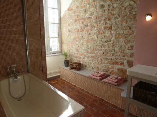La salle de bains est pourvue d'une baignoire et d'un mur en briques. dans l'établissement Château de Clusors, à Saint-Menoux