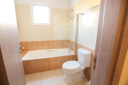 a bathroom with a toilet and a bath tub at Carisa Livadia Gardens in Livadhia