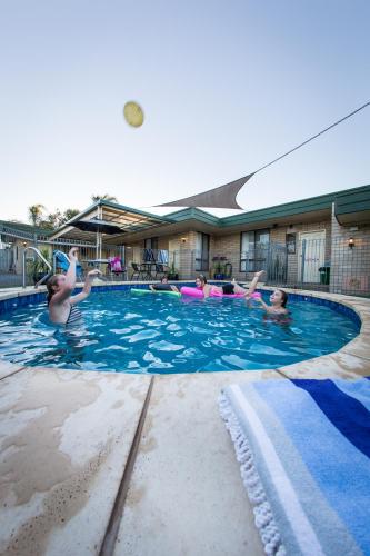a group of people playing with a frisbee in a swimming pool at 7th Street Motel in Mildura