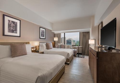セブシティにあるSeda Ayala Center Cebuのベッド2台、薄型テレビが備わるホテルルームです。