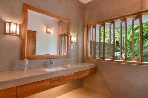a bathroom with a sink and a mirror and windows at Niketh Villa Kandy in Kandy