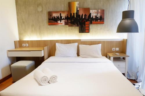 a bedroom with a bed with white sheets and pillows at Parquette Studio at Paramount Skyline Apartment By Travelio in Tangerang