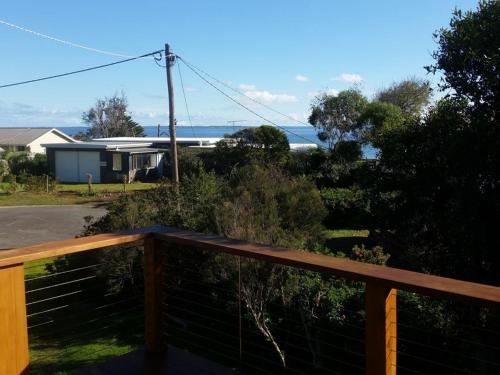 a wooden deck with a view of a house and the ocean at 4 Bounty in Corinella