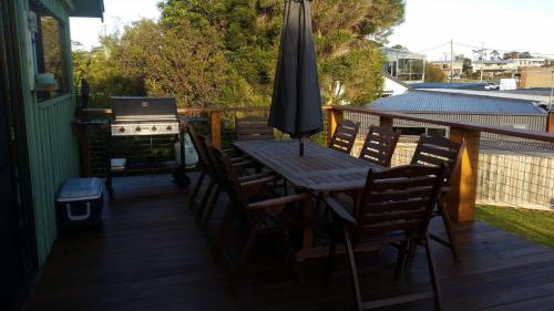a wooden table with chairs and an umbrella on a deck at 4 Bounty in Corinella