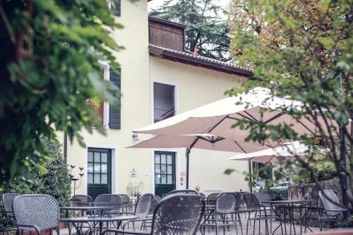 un gruppo di tavoli e sedie con ombrelloni di fronte a un edificio di Locanda Orologio a Cormòns