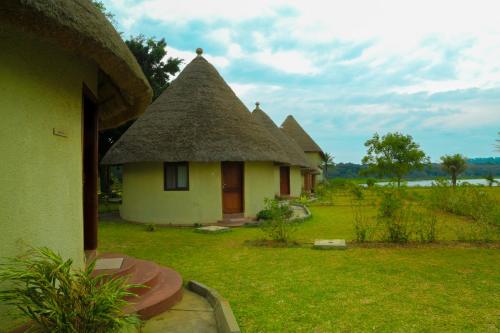 a group of cottages with a thatch roof at Victoria Forest Resort in Kalangala