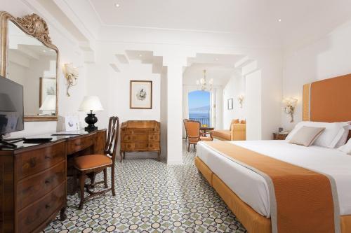 Habitación de hotel con cama, escritorio y TV. en Grand Hotel Ambasciatori en Sorrento