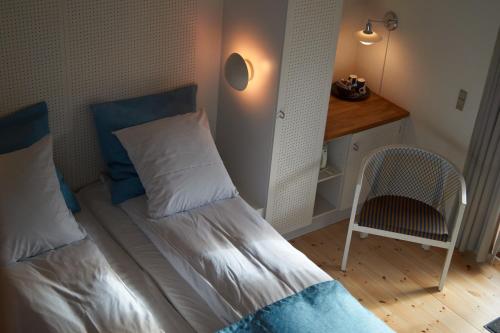a small bedroom with a bed and a chair at Henne Mølle Å Badehotel in Henne Strand