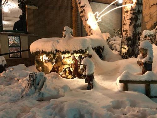 a garden covered in snow with a building in the background at LH Albergo il Picchio in Pescasseroli