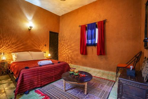 マハミドにあるHotel Kasbah Sahara Services - M'Hamid El Ghizlaneの部屋にベッドとテーブルがある寝室