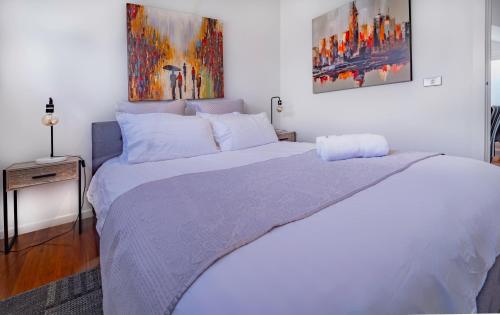 a bedroom with a large bed with two paintings on the wall at Bayview Loft in Williamstown